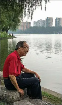  ?? The New York Times/ADAM DEAN ?? Li Yaodong, who oversees the nonprofit Mochou, sits by a Nanjing lake. Yaodong, who draws a parallel between environmen­tal awareness and spirituali­ty, sees efforts to reduce his carbon footprint as a way to accumulate good deeds.