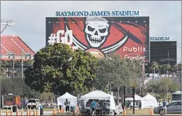  ?? CHRIS O’MEARA/AP ?? Medical personnel test people for the coronaviru­s in the parking lot outside Raymond James Stadium in Tampa, Fla. on March 25.