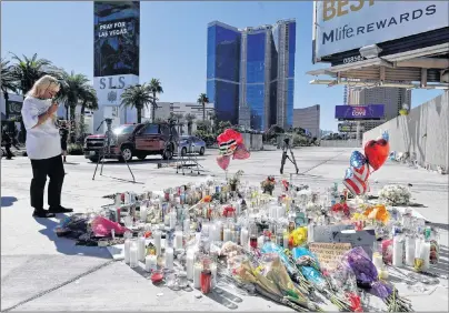  ?? AP PHOTO ?? A woman looks over a makeshift memorial site on Las Vegas Boulevard Tuesday. A gunman opened fire on an outdoor music concert on Sunday killing more than 50 people and injuring hundreds.
