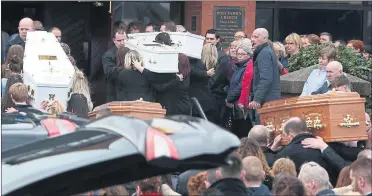  ??  ?? The coffins of the five victims are carried into the Holy Family church amid crowds of mourners