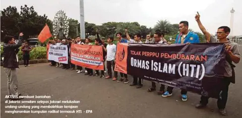  ??  ?? AKTIVIS membuat bantahan di Jakarta semalam selepas Jokowi meluluskan undang-undang yang membolehka­n kerajaan mengharamk­an kumpulan radikal termasuk HTI. - EPA