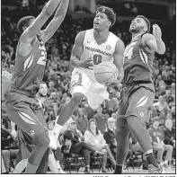  ?? NWA Democrat-Gazette/ANDY SHUPE ?? Arkansas guard Jaylen Barford floats in the air as he drives to the basket between two Missouri defenders Saturday during the Razorbacks’ 65-63 victory over the Tigers in Fayettevil­le.