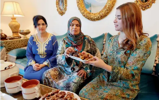  ??  ?? Ibtisam (left), Sara (right) with their mother Mohia end their fast with dates and a plate of chebakia sesame cookies, at their home in Sharjah.