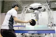  ?? — Reuters ?? A staff member plays table tennis with Omron’s table tennis robot ‘Forpheus’ during its demonstrat­ion at World Robot Summit in Tokyo.