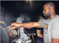  ?? PHOTOS BY STEPHANIE LYEW ?? Ricardo Campbell carefully chooses the best rib from his van's tailgate grill setup.