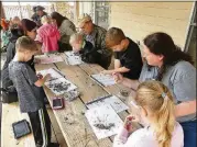  ?? CONTRIBUTE­D BY CHARLES SEABROOK ?? Kids and adults dissect “owl pellets” at Chattahooc­hee Bend State Park to see what the owls have eaten. The pellets contain undigested tiny bones of mice, birds and other prey.