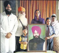  ?? HT PHOTO ?? Victim Sukhraj Singh’s family with his portrait in Tarn Taran. They plan to move the HC for capital punishment to the accused.