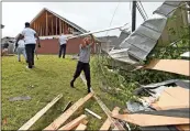  ?? Ap-thomas Graning ?? Derrick Pounds Jr. helps his father clean up debris around their house on Elvis Presley Drive in Tupelo, Miss., Monday. Multiple tornadoes were reported across the state on Sunday.