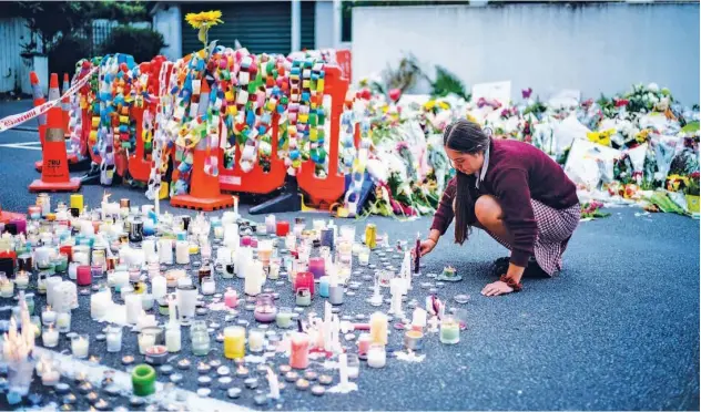  ?? Agence France-presse ?? ↑ A student places a candle next to flower tributes for the victims after a vigil in Christchur­ch on Monday.