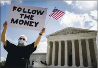  ?? ANDREW HARNIK — THE ASSOCIATED PRESS ?? Bill Christeson holds up his sign, “Follow the Money,” outside the Supreme Court on Thursday in Washington.