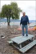  ?? GARY NYLANDER/The Daily Courier ?? Watt Road resident Michael Neill surveys debris and water covering his beach from a picnic table on Wednesday.