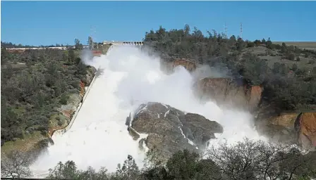  ??  ?? Overflow: Water flowing down the emergency spillway at the Oroville Dam for the first time in its nearly 50-year history after heavy rainfall. — AP