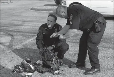  ?? NWA Democrat-Gazette/BEN GOFF • @NWABENGOFF ?? Deputy Joe Pruitt (left) and Sgt. Larry Hockenberr­y with the Benton County Sheriff’s Office look over contents Thursday of a backpack found in the parking lot south in Bentonvill­e. Police said the backpack contained drug parapherna­lia and a suspected controlled substance.