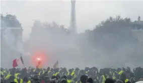  ?? (Photo: AFP) ?? Demonstrat­ors gather as tear gas fills the air during a protest of Yellow vests (Gilets jaunes) against rising oil prices and living costs on the Champs Elysees, near the Eiffel Tours, in Paris, on December 1, 2018.