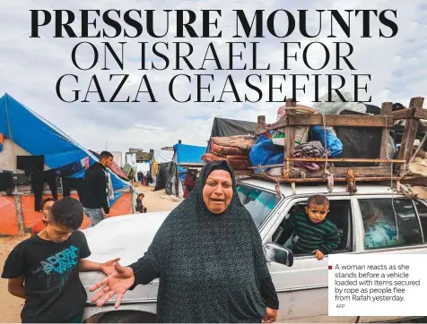  ?? AFP ?? A woman reacts as she stands before a vehicle loaded with items secured by rope as people flee from Rafah yesterday.