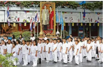  ?? FOTO: WALTON/EPA/DPA ?? Alltag in Thailand: Schulkinde­r stehen 2014 unter einem Bild des damaligen Königs Bhumibol Adulyadej und Königin Sirikit, während sie vor dem Unterricht die Nationalhy­mne singen und der Monarchie ihren Respekt erweisen.