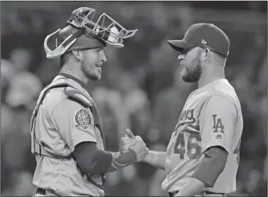  ?? Associated Press ?? Victory: Los Angeles Dodgers catcher Yasmani Grandal, left, and relief pitcher Josh Fields (46) celebrate after defeating the San Diego Padres in a baseball game Tuesday in San Diego. The Dodgers won 7-3.