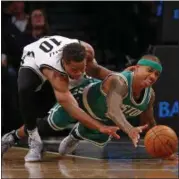  ?? RICH SCHULTZ — THE ASSOCIATED PRESS ?? Nets guard Yogi Ferrell, left, and Celtics guard Isaiah Thomas battle for the ball during the first half of Wednesday’s game in New York.