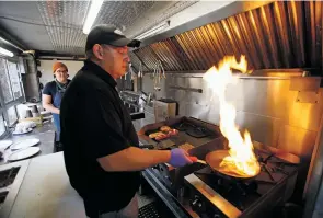  ??  ?? Jon Baker of Santa Fe, above, a cook with Root 66 food truck, prepares a black bean, spicy Italian sausage served with caramelize­d peppers and onions, right, Monday outside Santa Fe Brewing Co.’s Brakeroom location. Everything at Root 66 is 100 percent free of animal products.