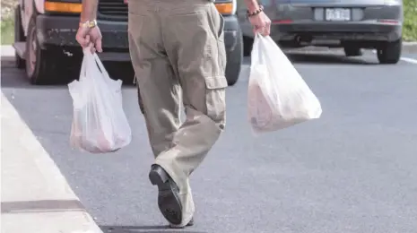  ?? CP PHOTO ?? A shopper leaves a grocery store carrying his groceries in plastic bags in Brossard, Que., in August 2016.