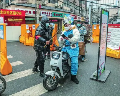  ?? EFE ?? Un voluntario comprueba el código sanitario que certifica que no se tiene covid-19 a un motorista en Wuhan