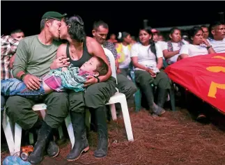  ?? GETTY IMAGES ?? Farc guerrillas ‘‘Willington’’ and ‘‘Veronica’’ kiss while holding their nephew at the conference to ratify the peace deal ending the 52-year guerrilla war between the Marxist rebels and the Colombian state.