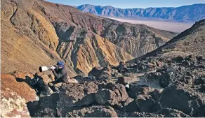  ??  ?? Jason O. Watson looks through a telephoto lens in February on a cliff overlookin­g Star Wars Canyon in Death Valley National Park, Calif. A growing number of photograph­ers and aviation enthusiast­s are visiting the park to catch a glimpse of fighter jets...