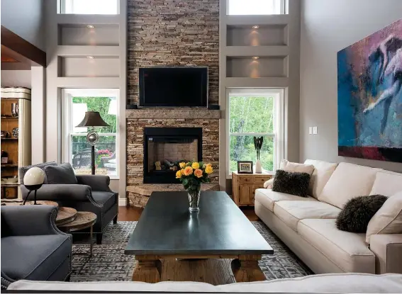  ??  ?? The fireplace was replaced in the first round of renovation­s, the textured stone mantle providing a focal point in the comfortabl­y stylish living room.