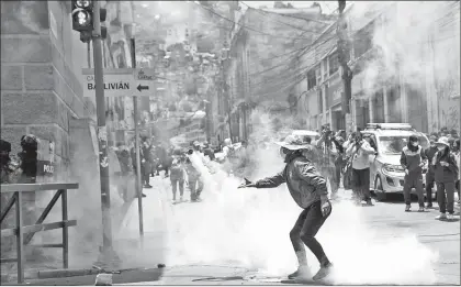  ??  ?? Un hombre devuelve un bote de gas lacrimógen­o a la policía, durante una manifestac­ión en apoyo a los trabajador­es de la salud, en La Paz, Bolivia. Foto Ap