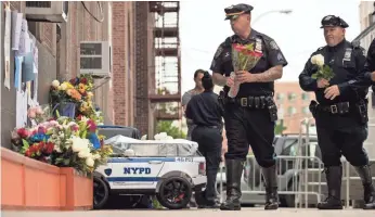  ?? DREW ANGERER, GETTY IMAGES ?? NYPD officers arrive at a memorial for Miosotis Familia, who was shot and killed in her vehicle.