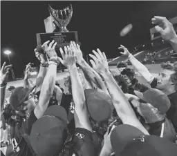  ?? ?? Hamilton players hoist the Class 6A championsh­ip trophy on Tuesday night at Tempe Diablo Stadium.