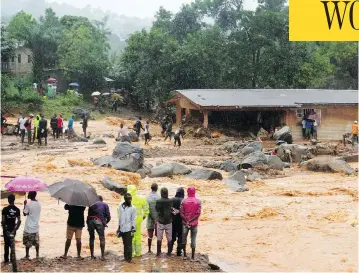  ?? SAIDU BAH / AFP / GETTY IMAGES ?? Bystanders look on as floodwater­s rage in Freetown on Monday, after landslides struck the Sierra Leone capital.