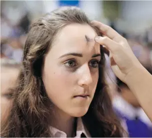  ?? JAE C. HONG/ THE ASSOCIATED PRESS ?? Madeline McFadden, 14, receives ashes on her forehead during an Ash Wednesday Mass at Santa Margarita Catholic high school in California on March 5 , marking the beginning of Lent when Christians practise self- restraint and pray in preparatio­n for...