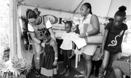  ?? CONTRIBUTE­D ?? Nicole Shim (left), administra­tive assistant at COK, assists with weighing children of COK members for their back-to-school medicals. The COK’s back-to-school fair took place at the credit union’s Slipe Road, Kingston, offices on August 10.