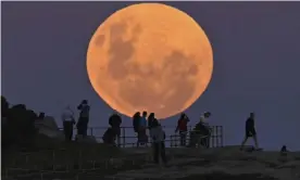  ?? Photograph: Anadolu Agency/Getty Images ?? People watch as the ‘super flower blood moon’ rises over Bondi Beach in Sydney on 26 May, 2021. Guardian Australia’s picture editor explains how to photograph the moon whether you’re using a phone or DSLR camera, and the best settings to use.