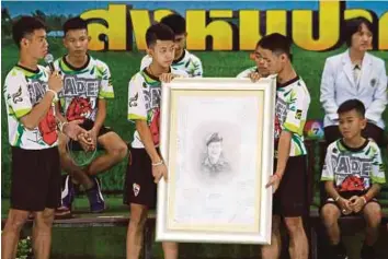  ??  ?? Dua belas remaja dan jurulatih mereka disambut meriah ketika menghadiri sidang akhbar di Chiang Rai, semalam. Remaja gua dan jurulatih pasukan berwajah sedih ketika memberi penghormat­an kepada potret Saman Kunan, pegawai SEAL yang terkorban ketika misi...