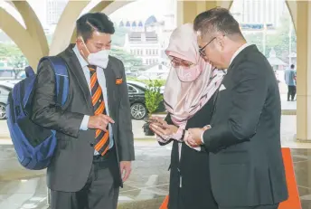  ?? ?? Tiang (right) and Engkilili assemblyma­n Dr Johnical Rayong Ngipa take an interest in something shown to them by Minister of Women, Childhood and Community Wellbeing Developmen­t Dato Sri Fatimah Abdullah prior to the start of the sitting.