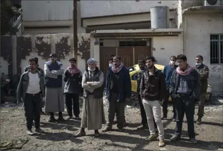  ?? FELIPE DANA, THE ASSOCIATED PRESS ?? Mahmoud Salem Ismail, second from right, other relatives and neighbours watch as civil protection rescue workers remove bodies of people killed in an airstrike in west Mosul, Iraq.