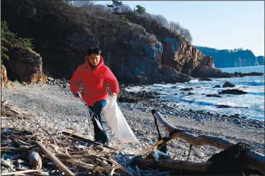  ?? (AP/Kang Dong Wan) ?? Kang picks up trash from North Korea on Dec. 21 on a beach of Yeonpyeong Island, South Korea.