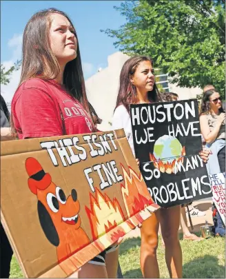  ?? THE OKLAHOMAN] ?? Brinkli Abbitt, left, and Gabrielle Lara, both 17-year-old seniors at Southmoore High School, hold signs while listening to a speaker Friday during the Oklahoma City Climate Strike, part of global rallies and marches to bring attention to climate change, outside of City Hall in Oklahoma City. [NATE BILLINGS/