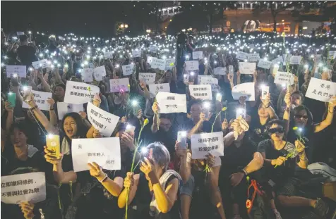  ?? GETTY IMAGES ?? People hold up smartphone lights and posters during a “mums protest” in Hong Kong on Friday night.