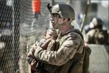  ?? Sgt. Samuel Ruiz/U.S. Marine Corps via AP ?? A Marine with Special Purpose Marine Air-Ground Task Force-Crisis Response-Central Command calms a child during an evacuation Thursday at Hamid Karzai Internatio­nal Airport in Kabul, Afghanista­n. Eleven Marines, one Navy sailor and one Army soldier were among the dead, while 18 other U.S. service members were wounded in Thursday’s bombing.
