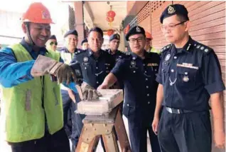  ??  ?? Azmi (right) with TNB personnel (left) cutting the power supply to premises, believed to be illegal gambling centres.