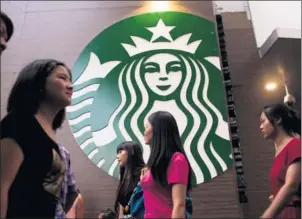 ?? BLOOMBERG ?? Pedestrian­s walk past a Starbucks Corp store in the Luohu district of Shenzhen.