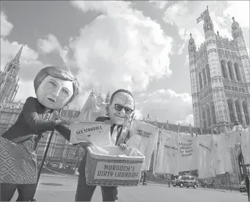  ?? Daniel Leal-Olivas AFP/Getty Images ?? ACTIVISTS posing as British Prime Minister Theresa May and media mogul Rupert Murdoch protest the proposed takeover of European satellite TV service Sky by Murdoch’s 21st Century Fox last week in London.