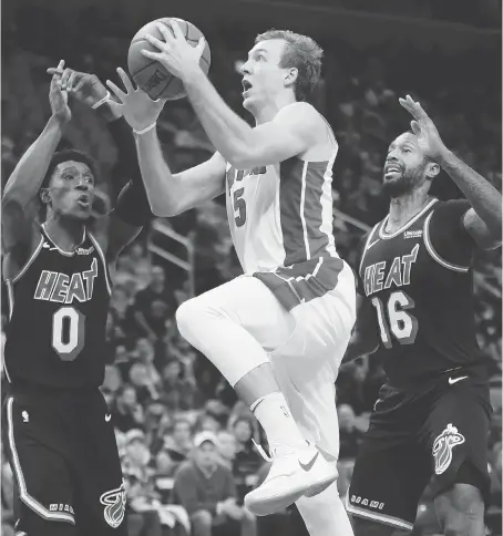  ?? DUANE BURLESON/THE ASSOCIATED PRESS ?? Detroit Pistons guard Luke Kennard goes to the basket against Miami Heat forwards Josh Richardson and James Johnson during second half NBA action on Sunday in Detroit. The Pistons are off to their best start since the 2005-2006 season.