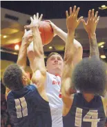  ?? GREG SORBER/JOURNAL ?? Connor MacDougall shoots over Utah State’s Alexis Dargenton (11) and Jalen Moore. MacDougall’s productivi­ty comes in timely fashion for a Lobos team that needs more inside help.