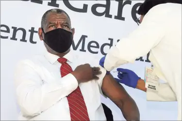  ?? Ned Gerard / Hearst Connecticu­t Media ?? The Rev. Carl McCluster,, of Shiloh Baptist Church, receives a COVID-19 vaccinatio­n during a news conference in front of St. Vincent’s Medical Center in Bridgeport on Friday. Nine Black and Latino clergy members from various Bridgeport ministries received vaccinatio­ns at the event.