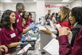  ?? ALYSSA POINTER / ALYSSA.POINTER@AJC.COM ?? Students of the Wellness Health and Education Academy at Snellville’s Shiloh High School hand out medicine bottles filled with candy during a ribbon-cutting ceremony for a new mock pharmacy lab, Feb. 15. Pharmacy tech students will earn college credit...