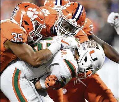  ?? MIKE COMER / GETTY IMAGES 2017 ?? Both Kirk and Cedric like Clemson to win its second national title in three years, largely because of its defense. Here, Tigers defenders engulf a Miami ball carrier in last season’s ACC championsh­ip game.